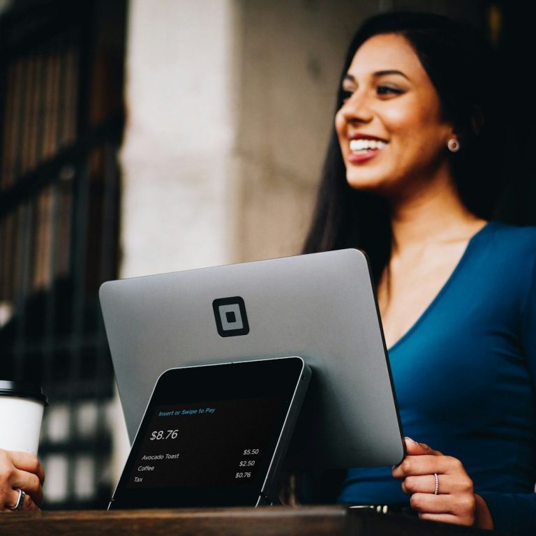 Bold Leadership Path Run Diagnostic Page Smiling woman in a blue top using a tablet at a café with a coffee cup.
