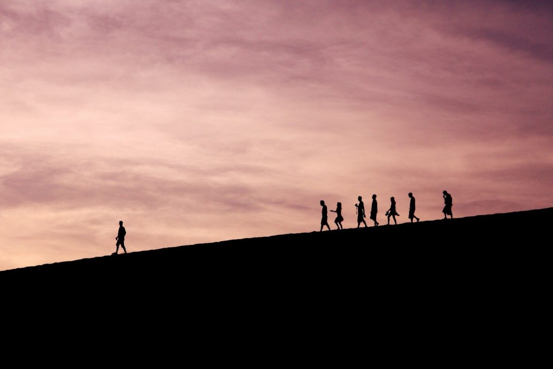 Bold Leadership Path The Method Page Silhouettes of people walking on a hill at dusk, with a purple sky.
